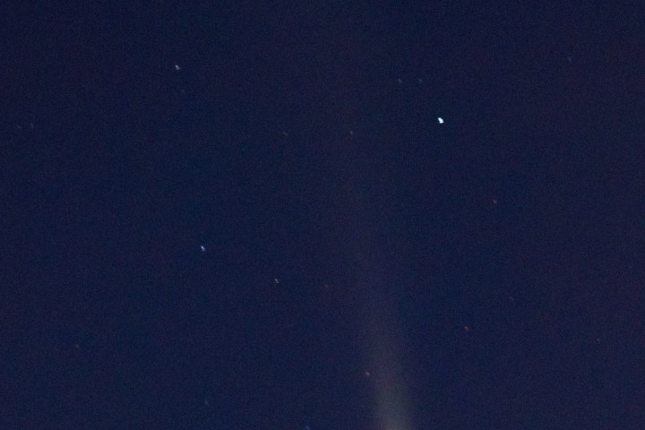 Comet with a bright tail in a starry night sky.
